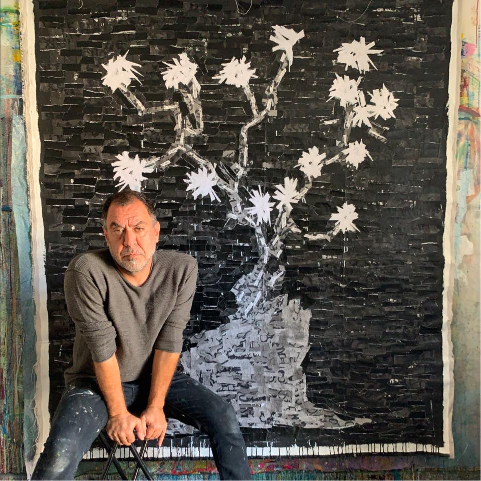 Farzad Kohan sitting next to his paintings of flowers